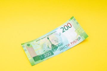 Two hundred ruble bill on a yellow paper background.