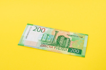 Two hundred ruble bill on a yellow paper background.