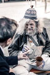 Rich man participating in act of charity while handing money to homeless
