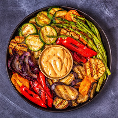 Grilled vegetables on a plate with sauce.