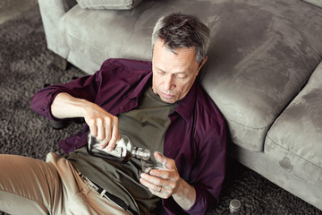 Attentive boozy short-haired guy pouring fresh portion of alcohol
