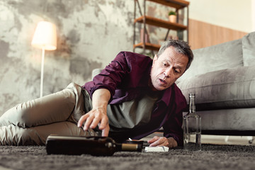 Desperate grey-haired guy reaching out for bottle of wine