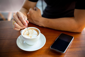 man use a small spoon in the coffee cup