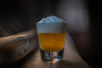 glass of beer with foam on black background