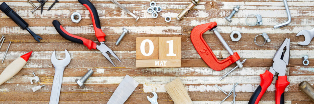 1st May. Happy International Worker's day or Labour Day Web banner background concpet.  wooden block calendar 1 May and handy tools on grunge wooden table texture background.