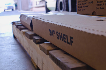 A pallet in the warehouse with the new shelfs packed in the back. 