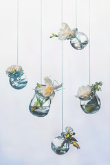 Flowers hanging in jars, white and yellow palette. Choosing items for an arrangement. DIY vase on a string with copy space.