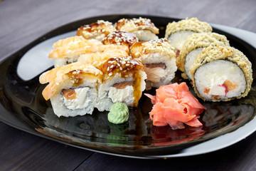 Sushi rolls with ginger and wasabi on a black plate