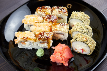 Sushi rolls with ginger and wasabi on a black plate