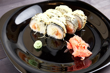 Sushi rolls with ginger and wasabi on a black plate