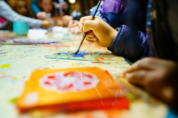 Fototapeta premium Child painted on a glass. traditional glass painting. child hand with nail polish. child painting a flower, stained glass. 