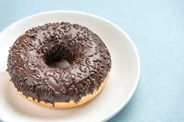 Chocolate donut on white plate on blue background