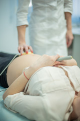 Obraz premium A gynecologist examines a pregnant woman. Fetal doppler heart auscultation. Patient at doctor office.