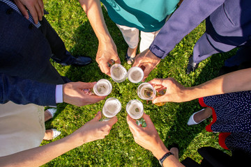 People hold in hands glasses with white wine. wedding party. friends toasting with a champagne in a park