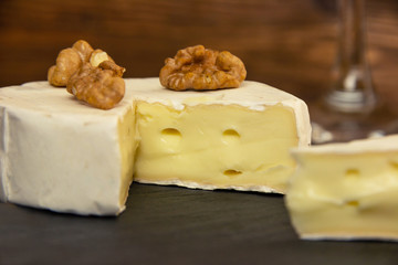 Fototapeta na wymiar Camembert chopped on a dark background with nuts