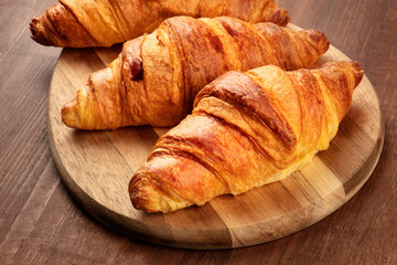 A closeup photo of three croissants on a dark rustic wooden background