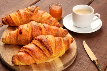 A closeup photo of a breakfast with croissants, coffee, and jam