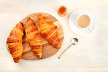 A high key photo of croissants with coffee and jam, shot from the top on a white wooden background with a place for text