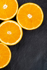 A closeup photo of orange halves, shot from the top on a black background with a place for text
