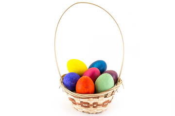 Colorfull Easter eggs in wicker basket isolated on white background