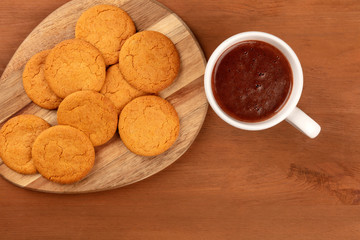 A closeup of gingersnaps, shot from the top with a cup of hot chocolate on a rustic wooden background with a place for text