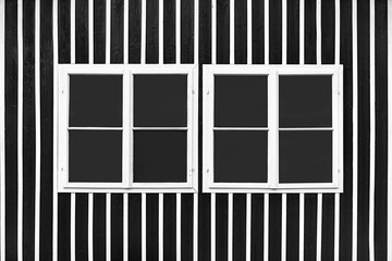 Two double white windows on a black wall with white slats.