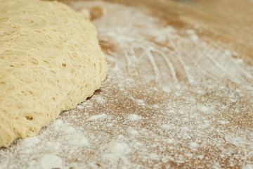 dough lying on a wooden cutting board sprinkled with flour