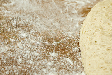 yeast dough lying on a wooden cutting board sprinkled with flour.