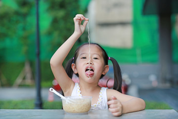 Cute little Asian child girl eating Instant noodles on the table.