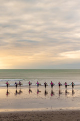 Fototapeta na wymiar Ten surfers running towards the sea.