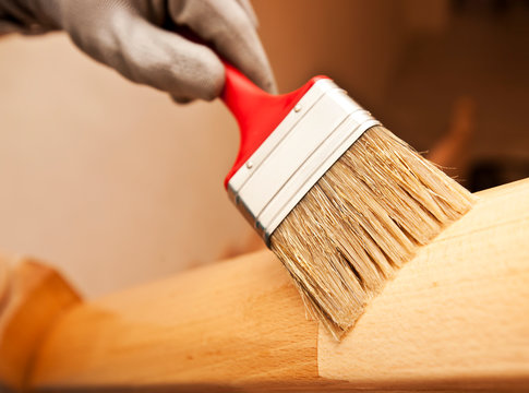 Woman paints a varnish wooden board by brush