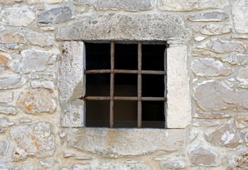 Fototapeta na wymiar Window with metal bars on old stone house