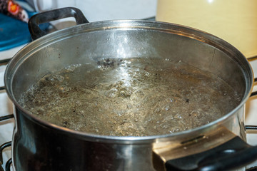 Boiling water for spaghetti or soup in a stainless steel pan on the kitchen stove at home