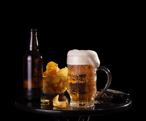 Evening male guests. Beer with foam in the glass, crisp chips, watching TV isolated on black