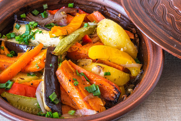Vegetarian dish, homemade tajine or tagine with potatoes, eggplants, zucchini and pepper, close-up - traditional Moroccan and Tunisian cuisine