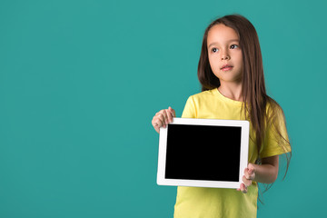 Fototapeta na wymiar cute little child girl holding tablet with blank screen isolated on blue background