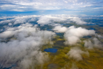 Flying in the sky above the clouds. Aerial photography. View of the tundra with small lakes. Arctic...