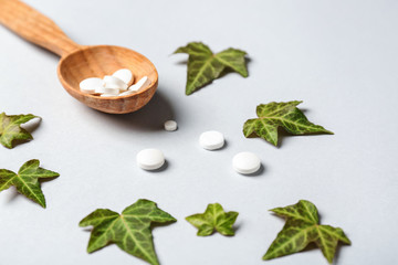 Spoon with plant based pills on light background