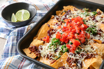 Baking dish with tasty nachos, minced meat, cheese and salsa on table
