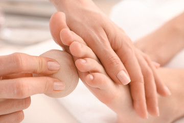 Fototapeta na wymiar Young woman receiving feet massage in spa salon