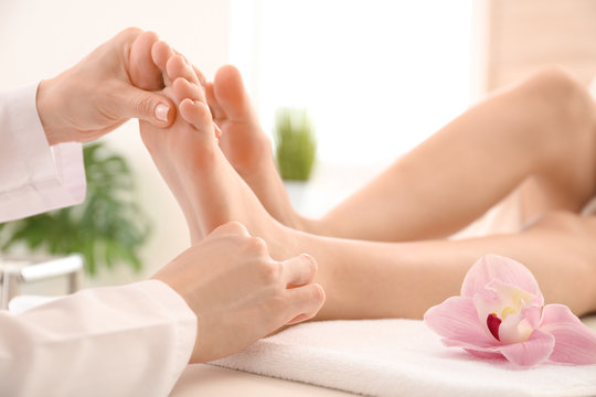 Young woman receiving feet massage in spa salon