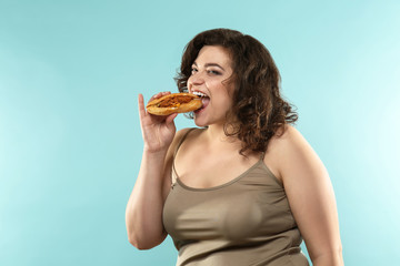 Overweight woman with sandwich on color background