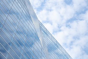 Cloud and sky reflected in the blue glass windows of building.