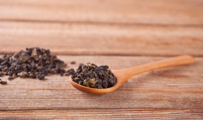 Black dry tea leaves with wooden spoon on the wooden table