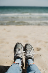 Fototapeta premium lifestyle picture of sneakers on the beach with white sand and seaview