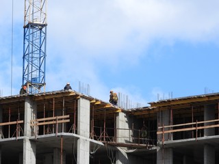 Large construction site, including several cranes working on the construction complex, with a clear blue sky.
