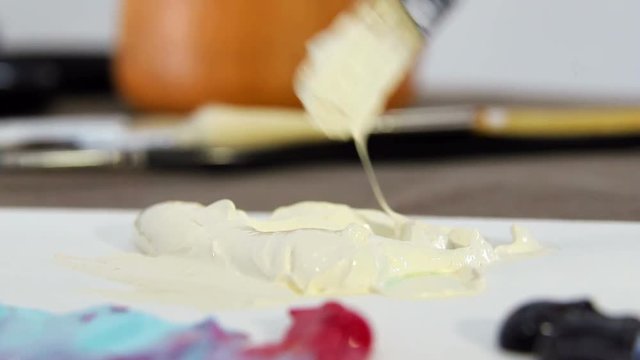 Artist brush mixes ivory paint on the palette to mix colors. Preparing to draw