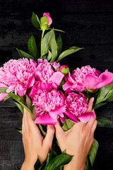  Hands of woman florist holding beautiful bouquet of peonies.
