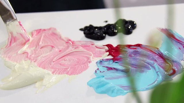 The artist mixes paint brush in ivory and red color palette for mixing colors. Preparing to draw