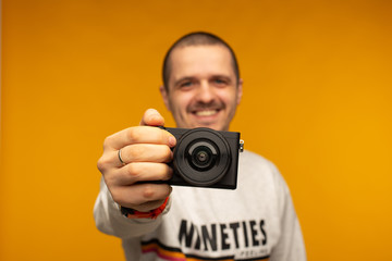 Photographer man holding mirorrless camera in his hand